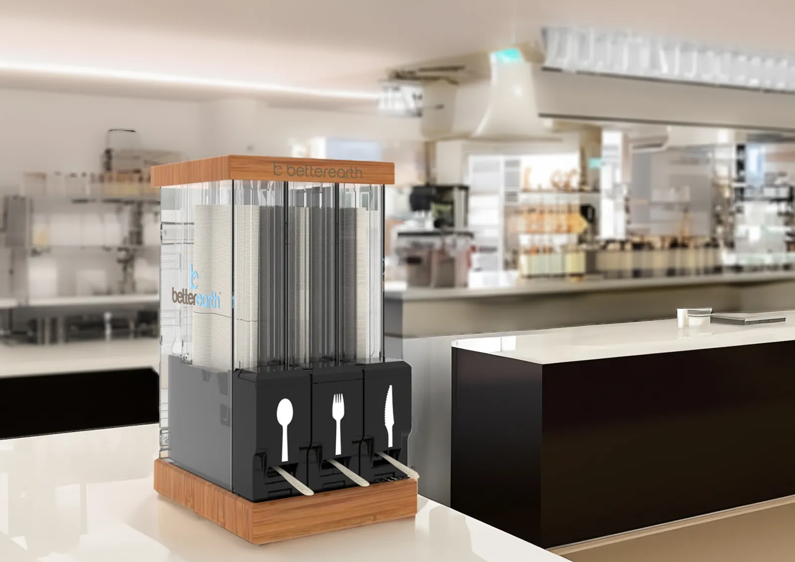 A dispenser with different sections for different types of cutlery -- spoons, forks and knives -- in a commercial kitchen setting.