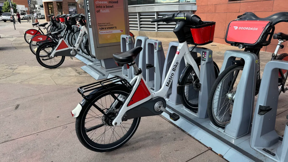 Several bicycles at a docking station on a street.