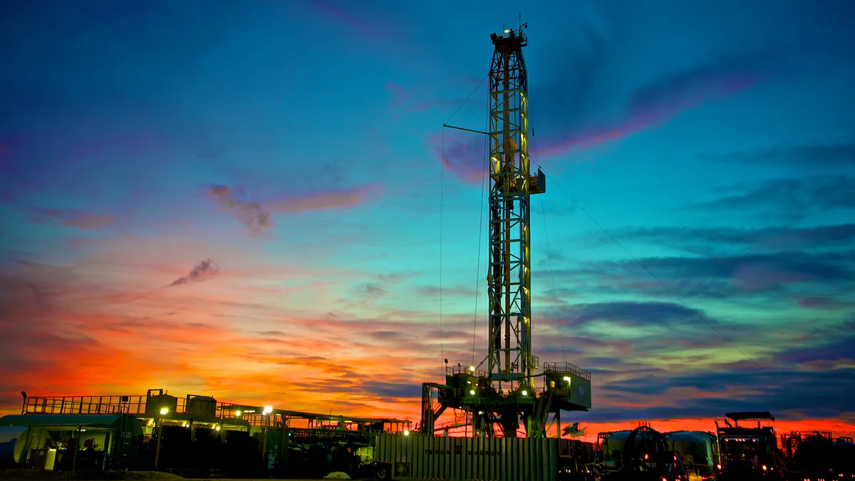 A photo of an oil rig at sunset.