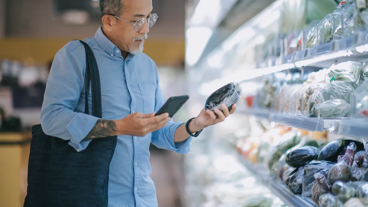 Person shopping with phone in the produce aisle at a grocery store