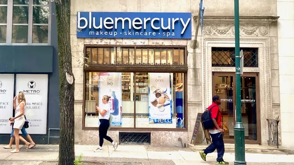 People walking down the street, past storefronts.
