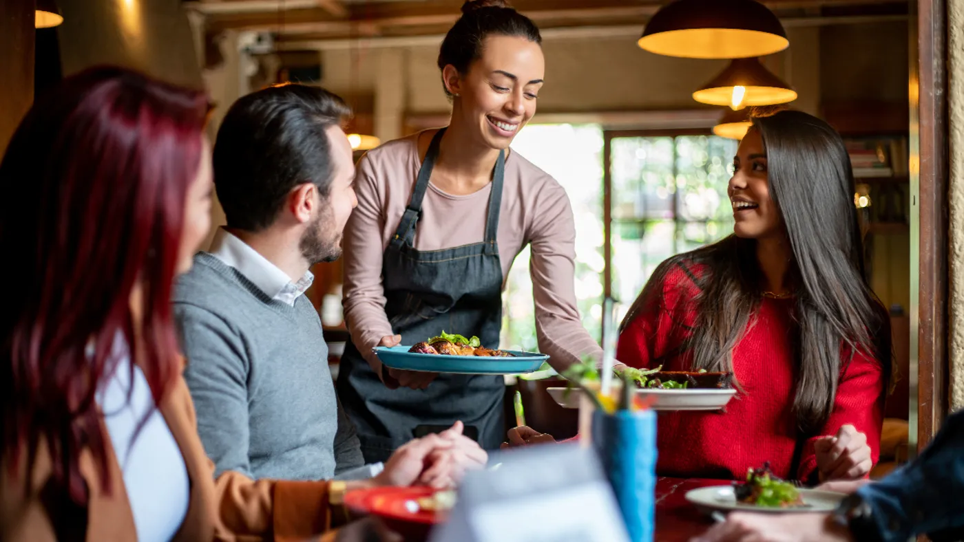 An image of a waitress serving three people at a table.