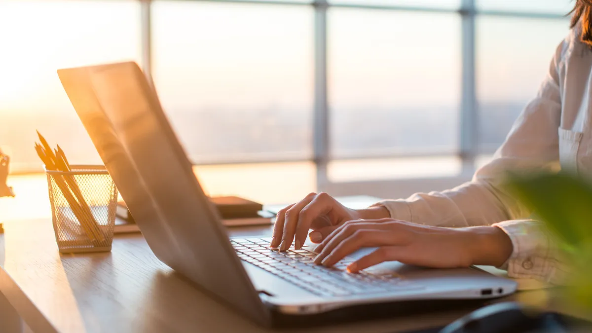 Female teleworker texting using laptop and internet, working online. Freelancer typing at home office, workplace.