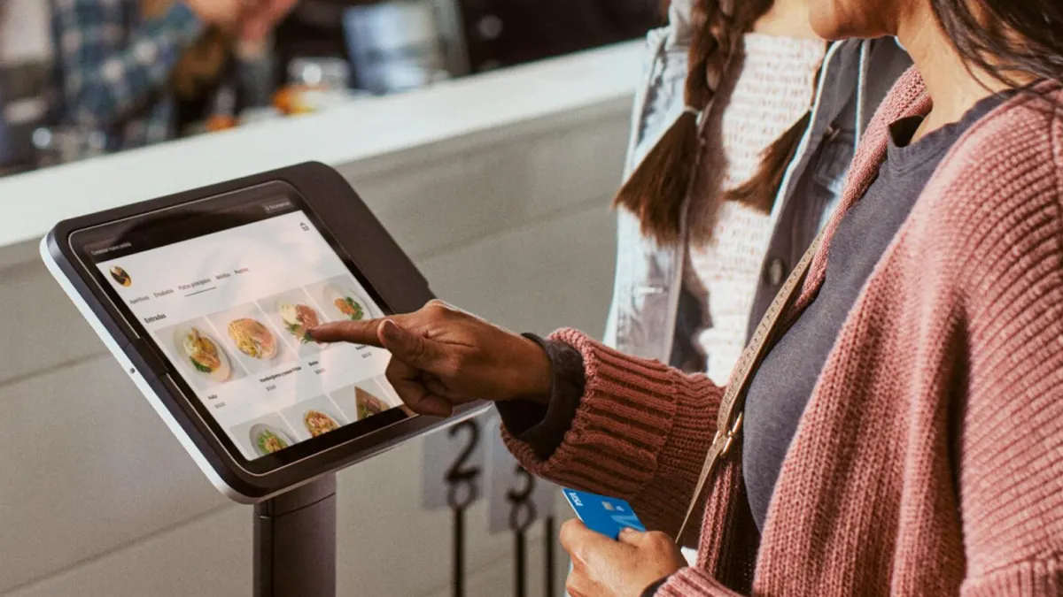 A person ordering food from a kiosk at a restaurant.