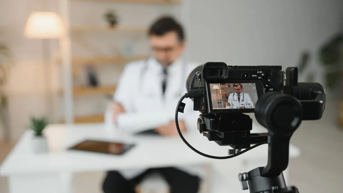 A focused image on a camera aiming on doctor looking down at papers