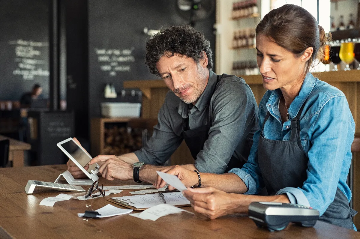 A man and woman looking at receipts inside a cafe