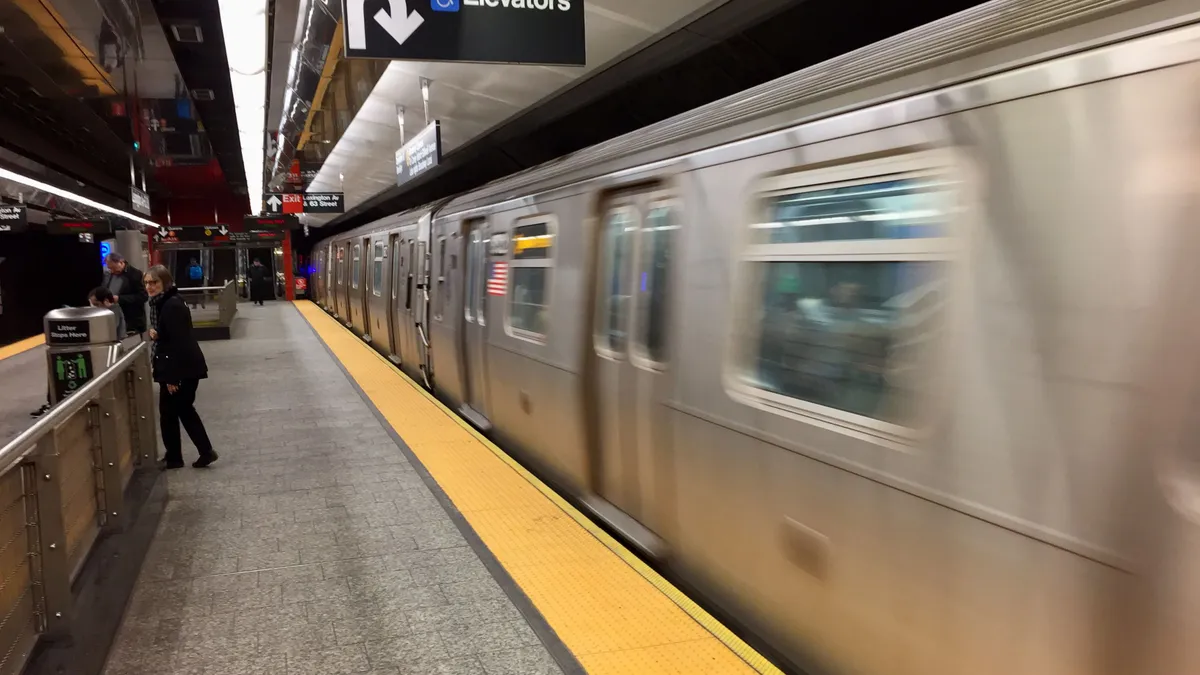 An aluminum New York City subway train at an underground station.