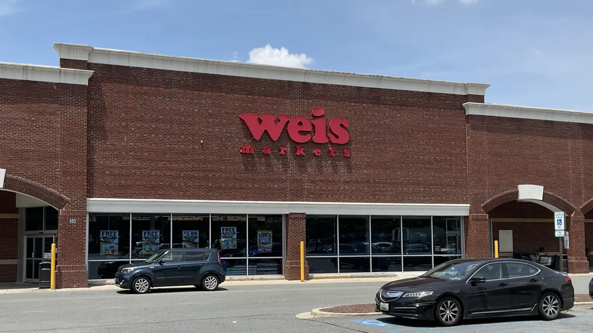 Exterior of supermarket with a dark brick front and a red sign reading "Weis."