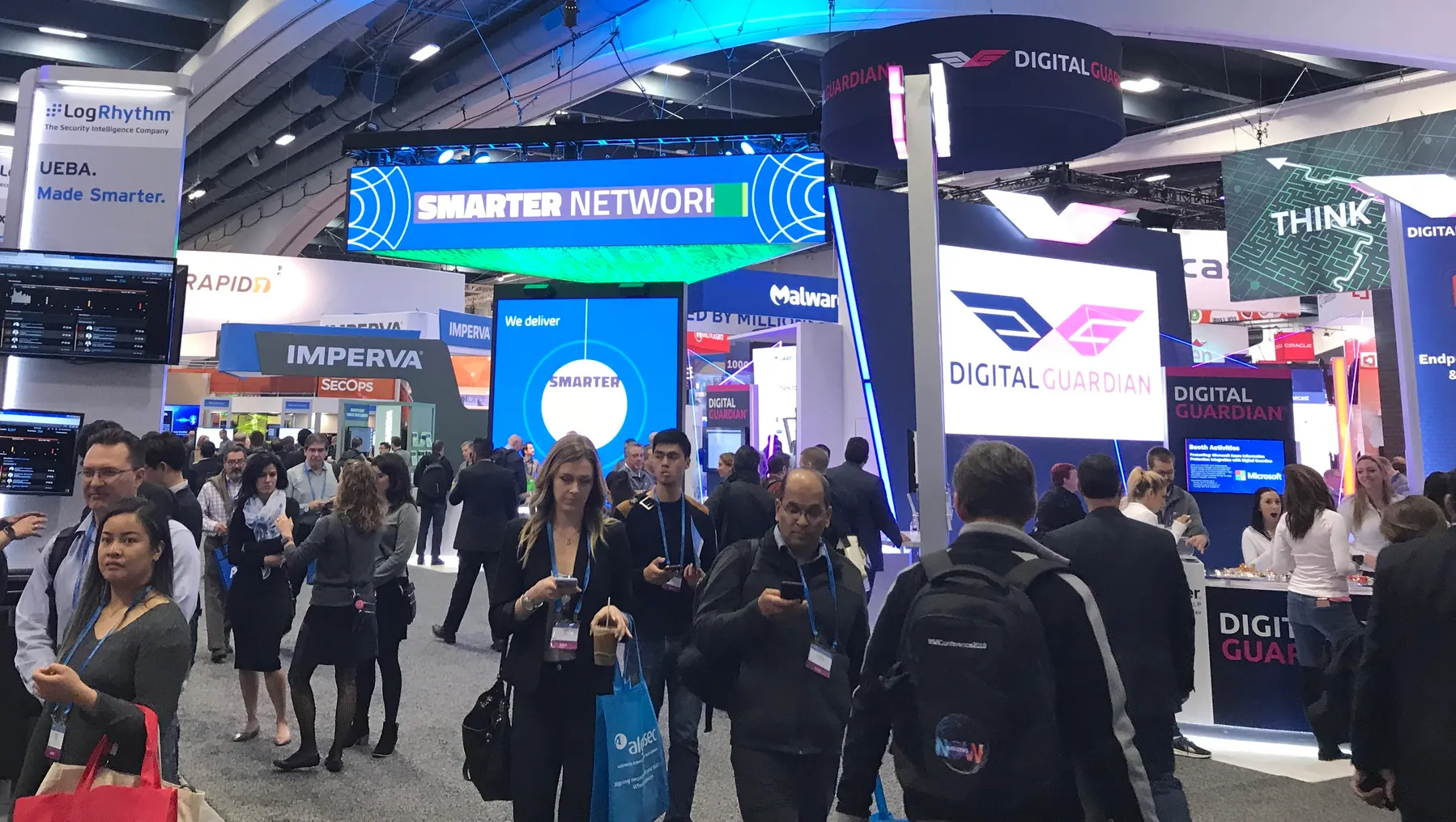 People gathering in an large room with different vendor signs.