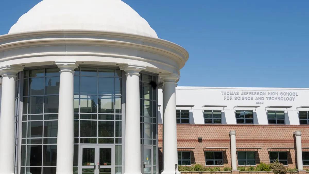 A school building is seen against a blue sky. On the building are the words Thomas Jefferson High School for Science and Technology 6560