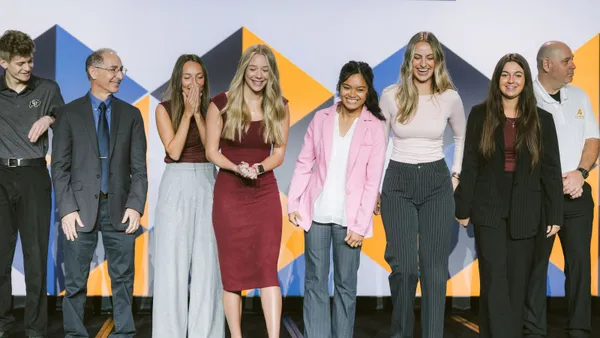 A group of people in professional stand and smile on a stage.