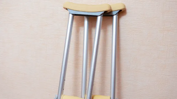 A pair of crutches leans against a wall