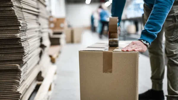 Worker taping cardboard box.