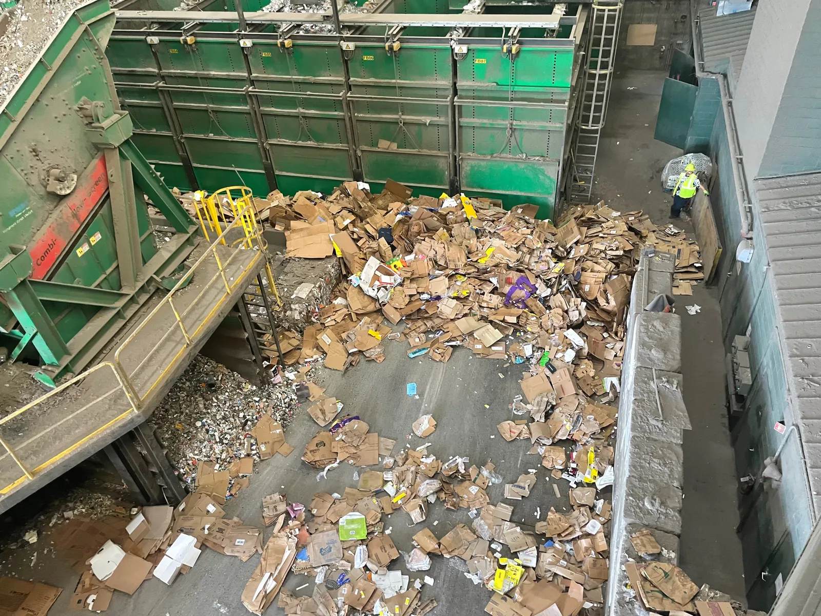 Worker next to cardboard pile at recycling facility