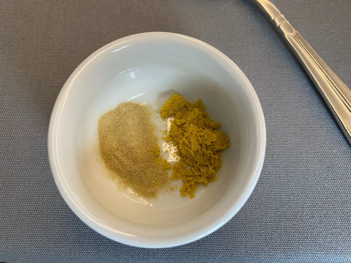Off white and yellow microalgae protein powder in a bowl.