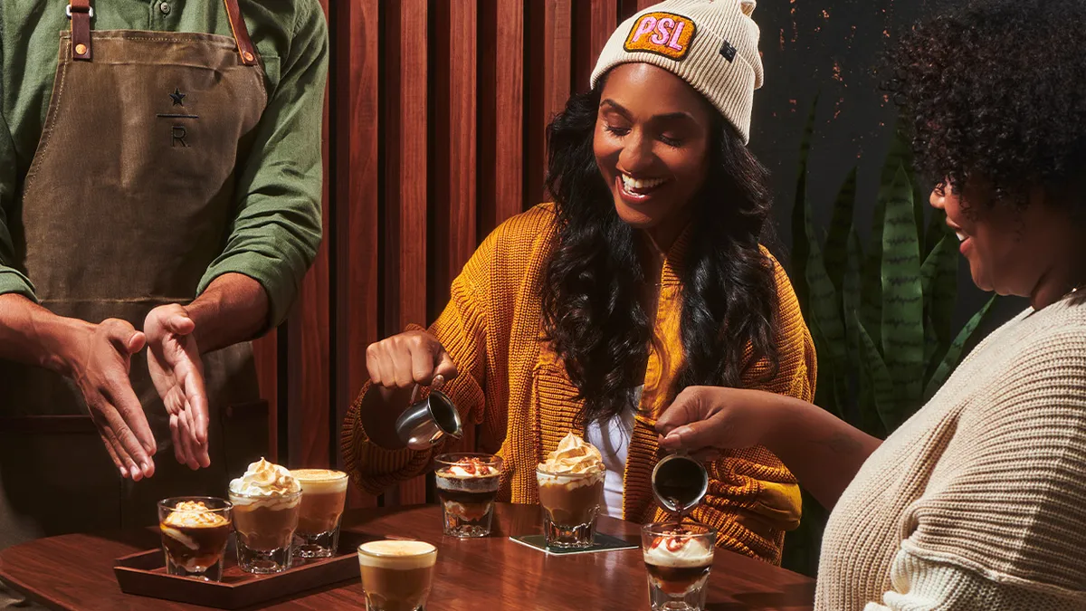 A person in a PSL hat sits at a table pouring something into a glass.