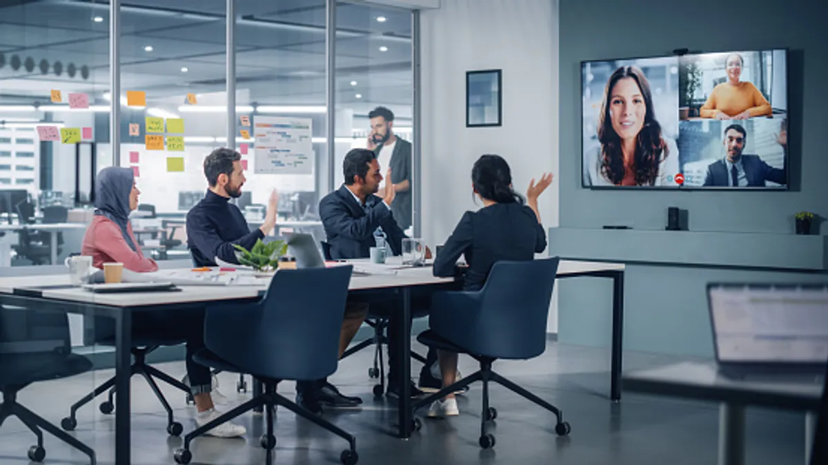 Team of people has a hybrid meeting with workers in-person and joining virtually via video chat