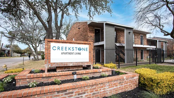 Creekstone Apartment Living sign next to brick, two-story apartments
