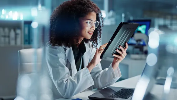 Tablet, laptop and woman scientist in lab working on medical research, project or experiment.