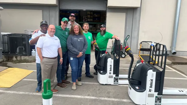 People stand around Bobcat pallet jacks.