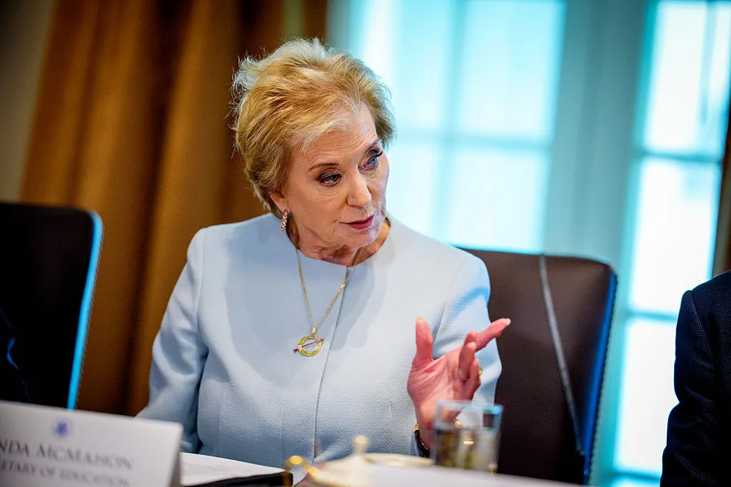 A person is sitting at a desk in a room. They are looking and pointing to their left.