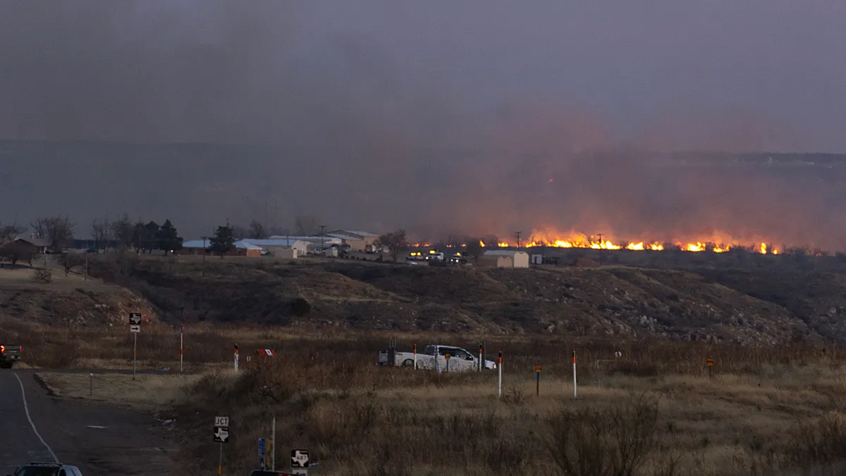 Buildings burn in the distance.