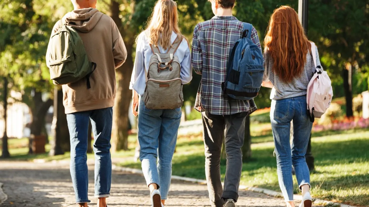 Students walking on campus with backpacks.