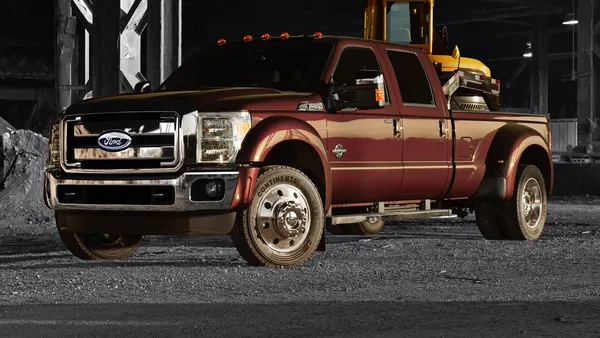 A 2015 F-450 Super Duty pickup parked outdoors on a gravel surface in front of an industrial building.