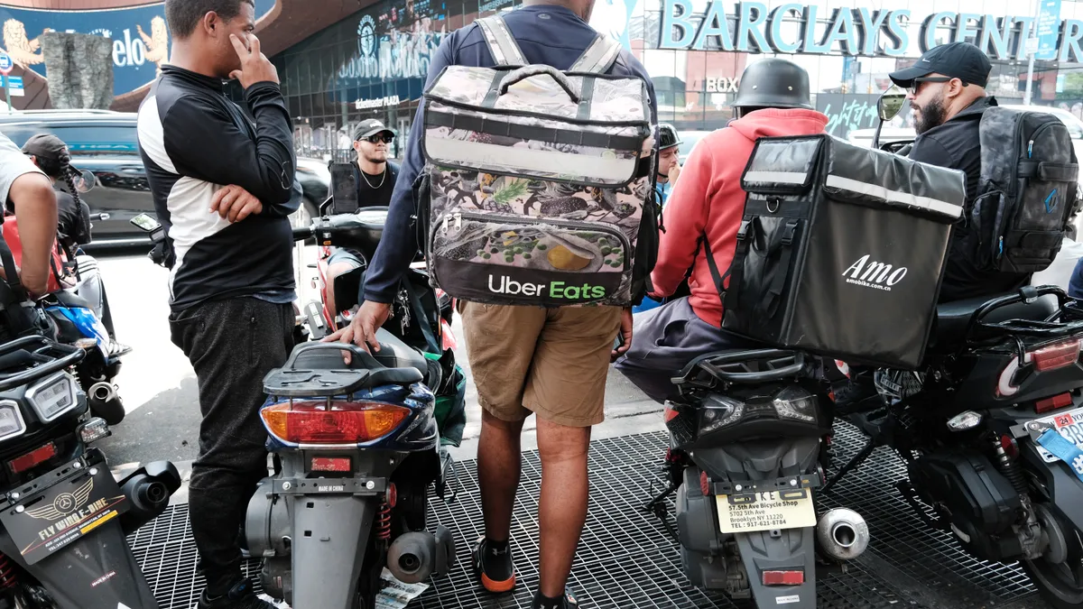 Bicycle gig workers congregate on the street with their packs.