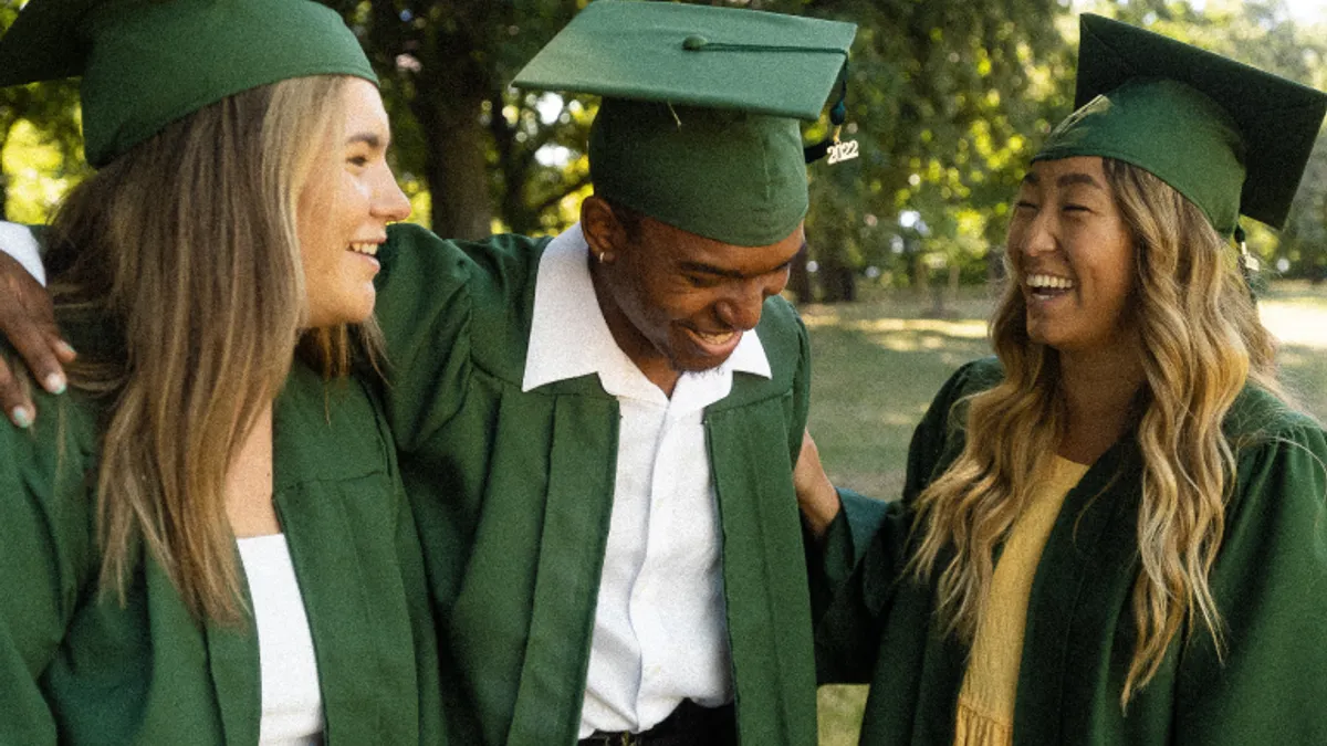 3 students dressed in graduation caps and gowns expressing joy