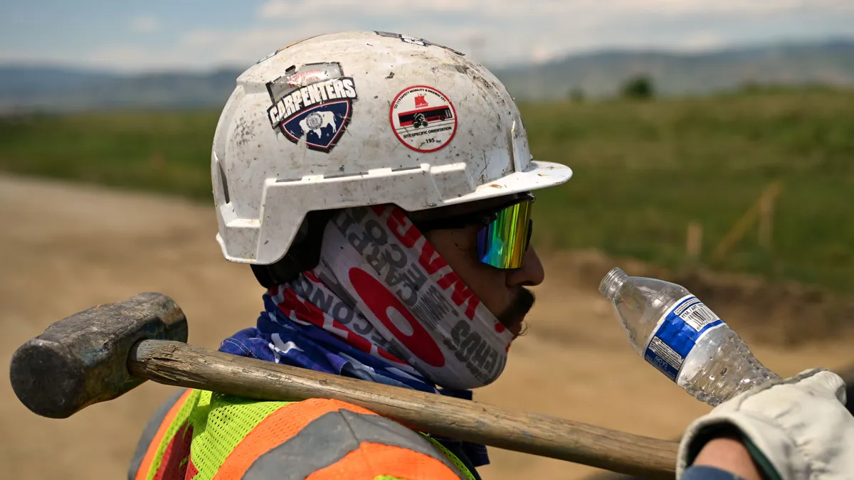 A construction worker sips water on a hot day.