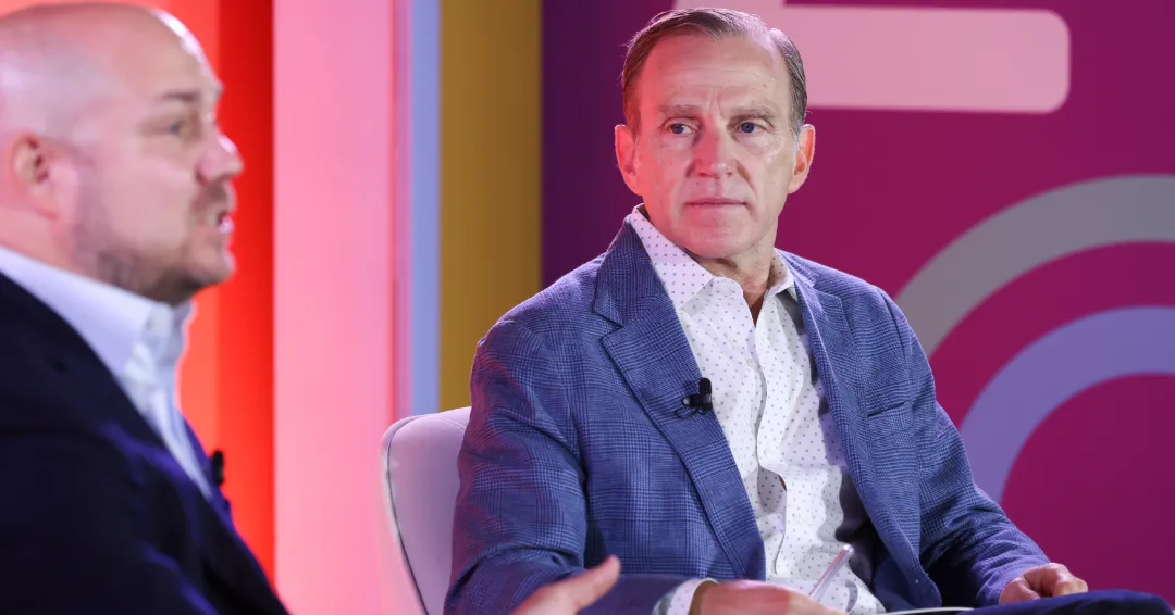 Two men sit on a colorful stage at Advertising Week 2024.