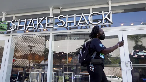 A person on a smartphone walks by a Shake Shack restaurant