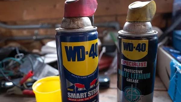 Two cans of WD-40 products sit on a workbench