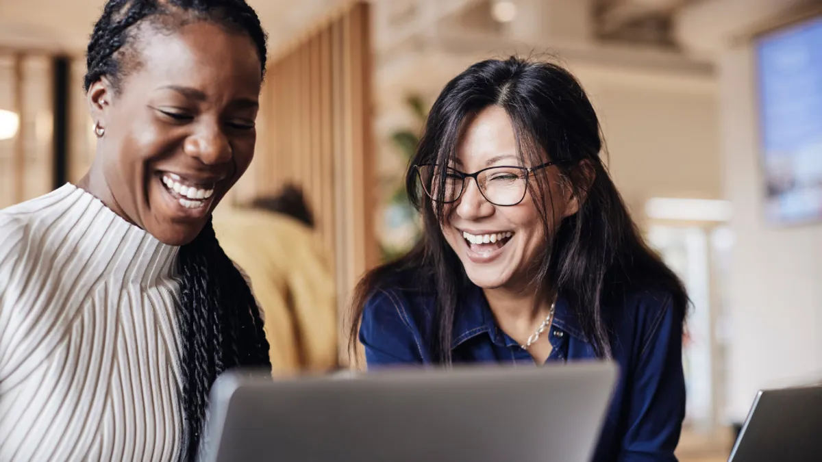 Two women laughing at a screen