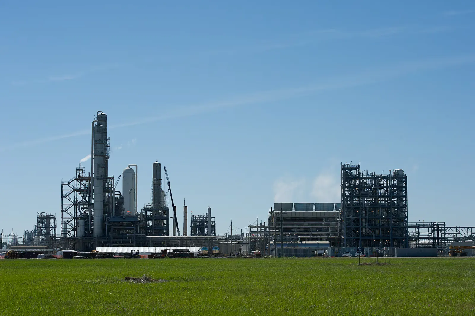 An outdoor chemical facility with a faint white smoke emitting from one of the units.