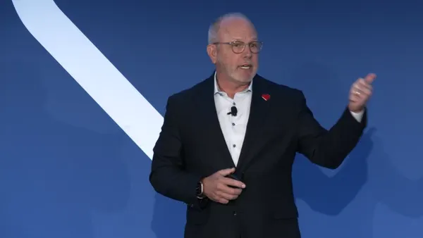 David Joyner speaks in front of a blue background.