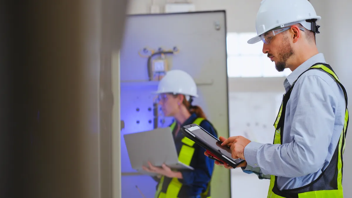 A technician inspects an electrical system in a control room.