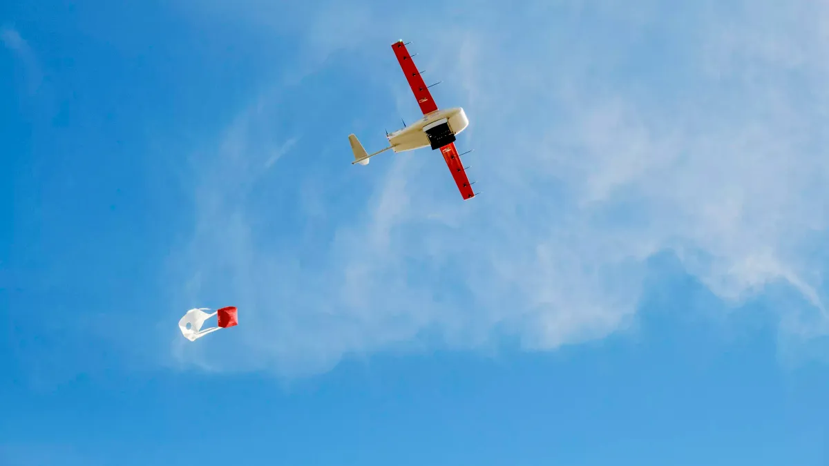 A Zipline cargo drone flies in a blue sky.