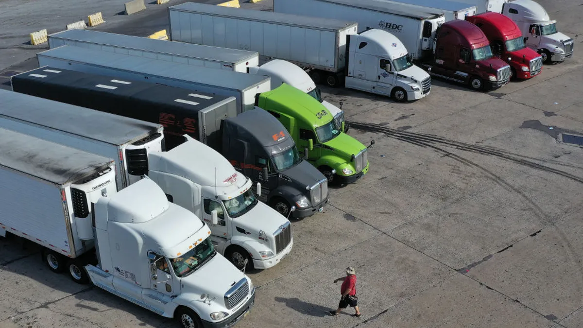 A person walks across a parking lot toward a series of trucks.