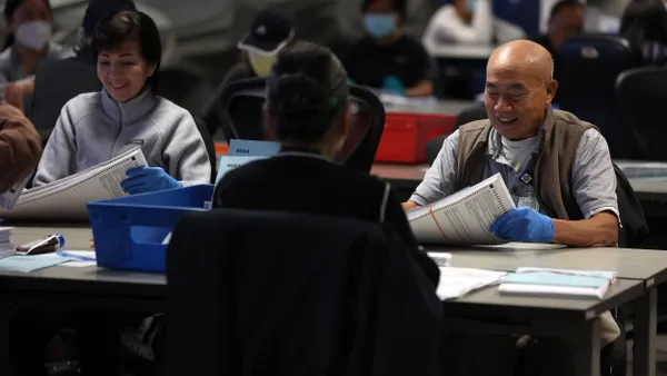 People sitting at desks sorting mail-in ballots.