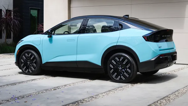 A light blue 2026 Nissan Leaf EV parked outdoors in front of a building.