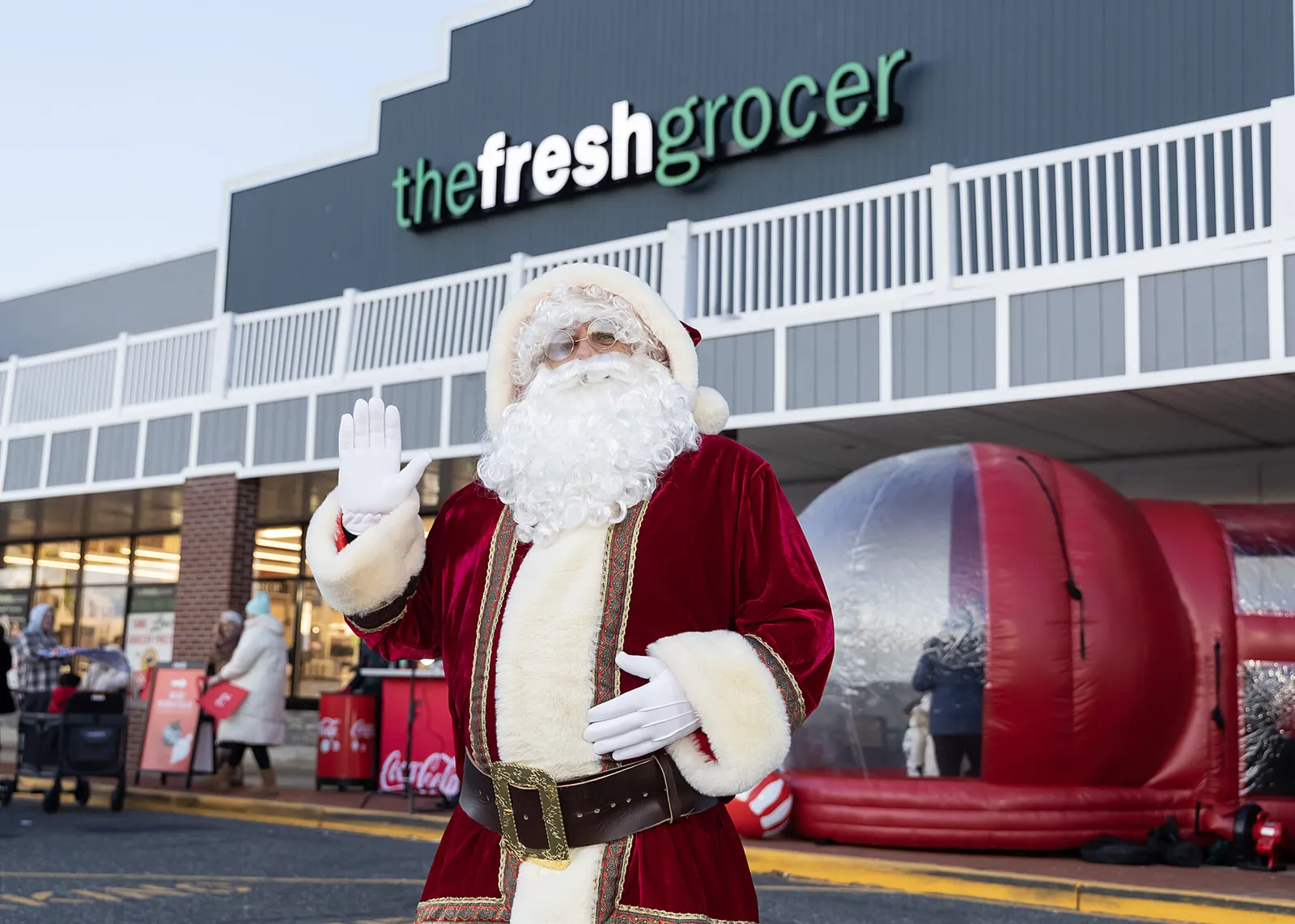 A person dressed as Santa outside of a grocery store.