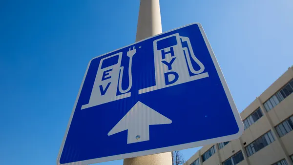 A sign showing electric and hydrogen fueling areas with an arrow pointing forward.