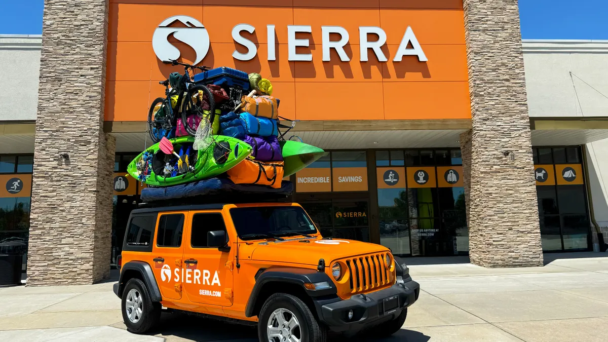 An orange Sierra-branded vehicle with outdoors products stacked on top.