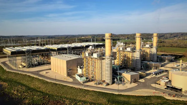 An industrial complex with three smokestacks in a rural setting.