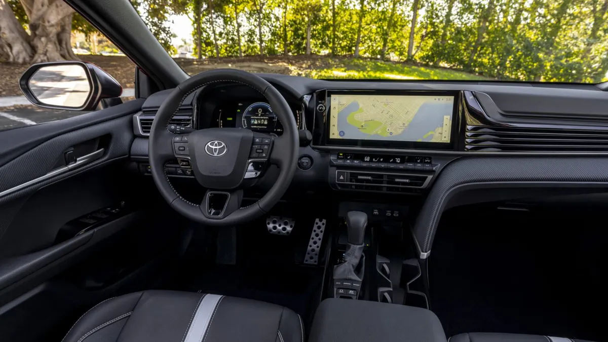 The dashboard and instrument cluster in a 2025 Toyota Camry Hybrid SE trim with a black interior.