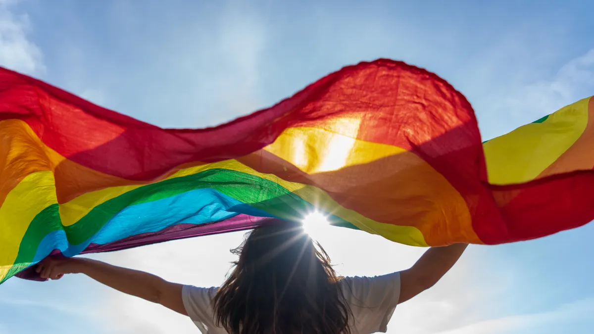 A woman waves a rainbow flag.