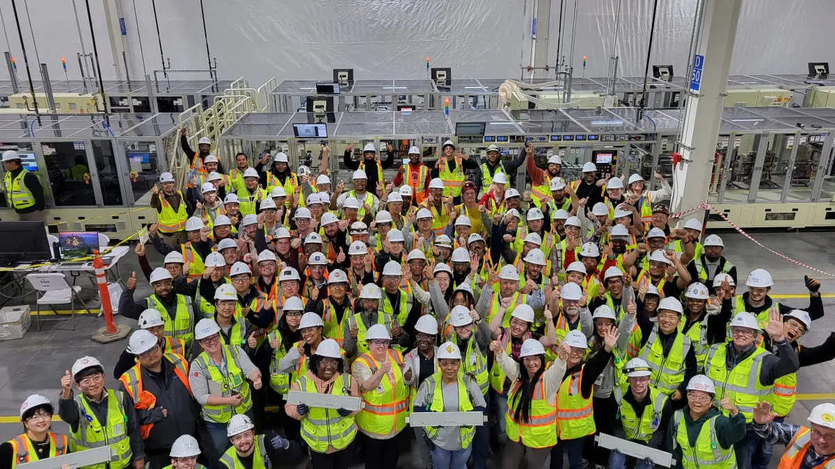 Manufacturing workers stand in a group in a factory