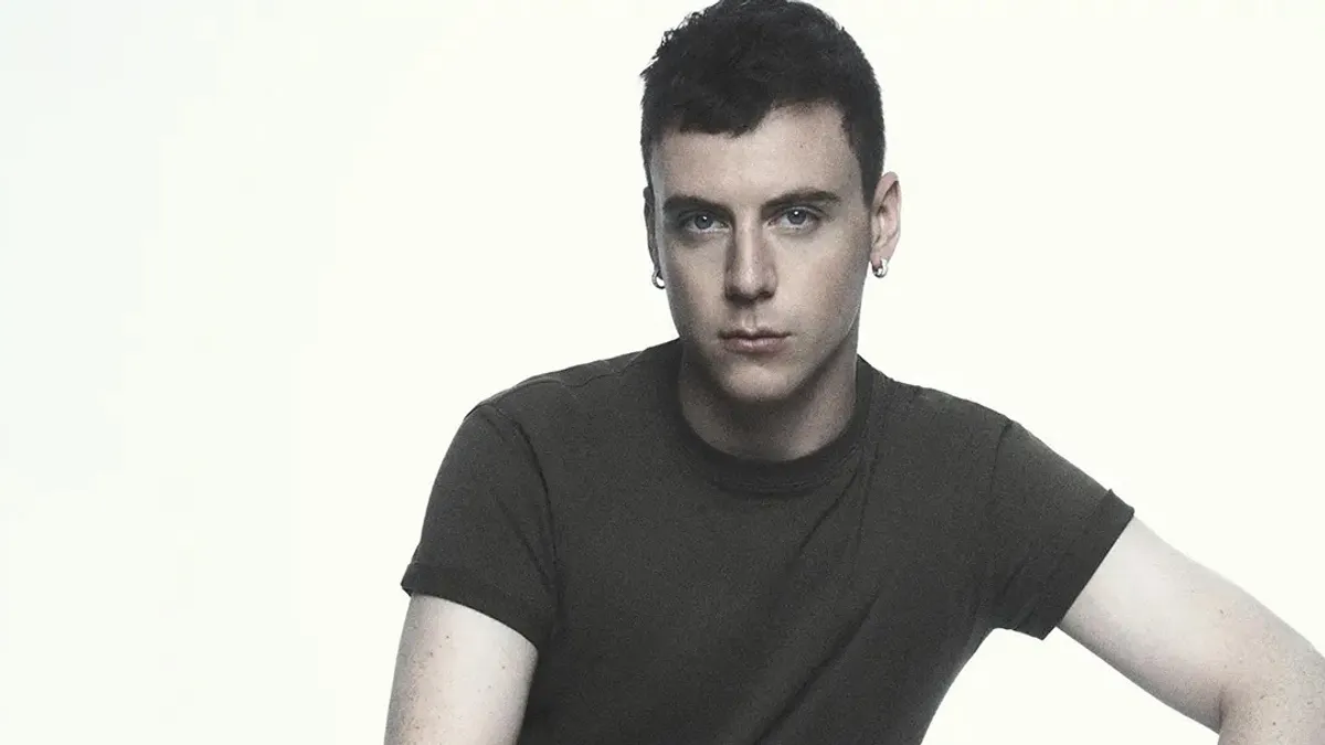 A man, Seán McGirr, wear a black t-shirt and stares into the camera.